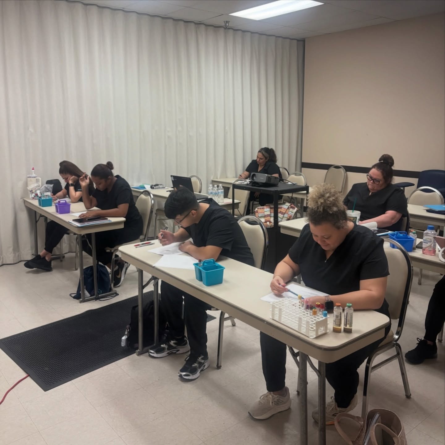 VMI students in black scrubs seated at desks during a classroom session with specimen tubes on tables